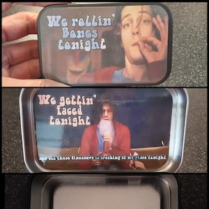 May include: A black metal tin with a colorful graphic of a person smoking a cigarette. The text on the tin reads "We rollin' Bones tonight" and "We gettin' faced tonight".