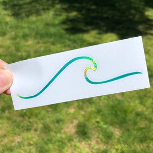May include: A teal blue wave sticker with iridescent glitter accents. The sticker is on a white background.