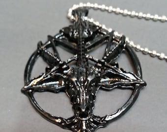 Könnte beinhalten: Schwarze Metallkette mit einem Anhänger in Form eines Pentagramms mit einem Ziegenkopf in der Mitte.