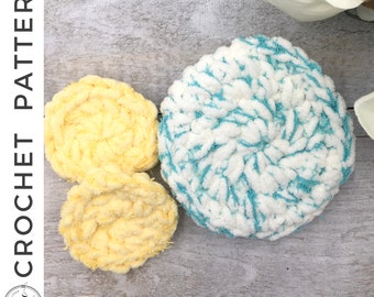 May include: Three crocheted flower shapes, one is yellow, one is white with blue accents, and one is a lighter yellow. The flowers are on a light wood background.