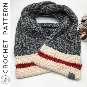 May include: A gray and white crocheted scarf with a cream and red striped trim. The scarf is folded in half and the ends are overlapping. The scarf has a small tag that says "The Loop Stitch Craft".