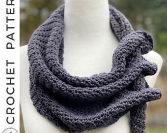 May include: A dark gray crocheted infinity scarf, displayed on a white mannequin. The scarf is made with a simple stitch pattern and has a long, flowing shape.