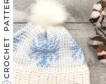 May include: White crochet beanie with a blue snowflake pattern and a white faux fur pom pom. The beanie has a white label with the text "The Loop Crochet" on it.