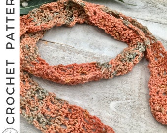 May include: A crocheted scarf in shades of orange and green. The scarf is made with a lacy stitch pattern and has a soft, textured look.