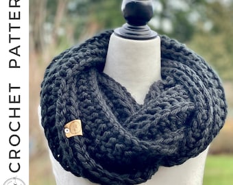 May include: A black crocheted infinity scarf with a brown tag that says "The Loop" on a white mannequin.
