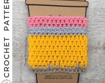 May include: A handmade crochet coffee cup sleeve in a pencil design. The sleeve features a yellow, gray, and pink color scheme. The text "CROCHET PATTERN" is on the left side. The bottom of the sleeve has the text "HERE'S A LITTLE GIFT TO ESPRESSO MY GRATITUDE!"