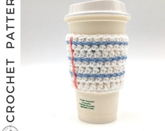May include: White crocheted coffee cup cozy with blue and pink stripes. The cozy is on a white disposable coffee cup.