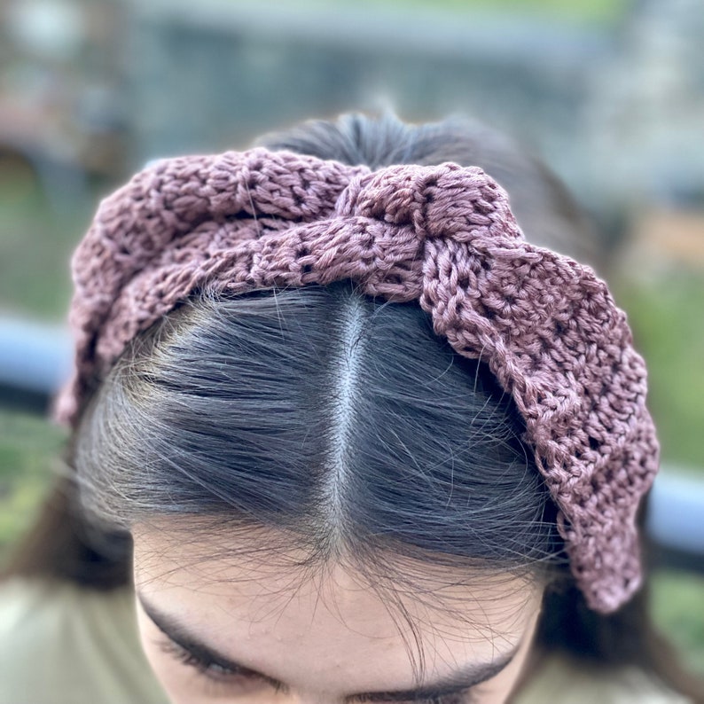 May include: A mauve crocheted headband with a knotted bow detail.
