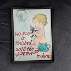 May include: Framed vintage artwork depicting a baby on a potty, holding a toy, with a toilet roll in the background. The text reads "NO JOB is finished until the PAPERWORK is done" in red letters.