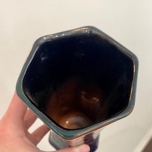 K&ouml;nnte beinhalten: Eine blaue und braune Keramikvase mit einer sechseckigen &Ouml;ffnung. Die Vase hat eine gl&auml;nzende Oberfl&auml;che.