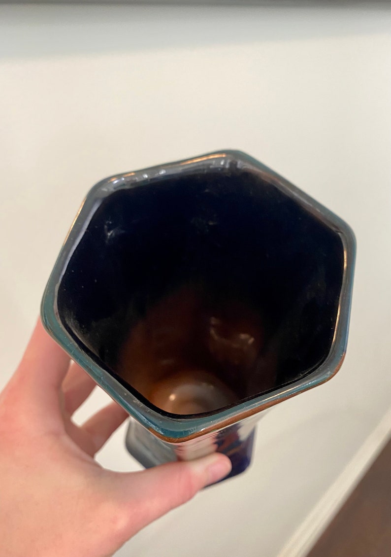 K&ouml;nnte beinhalten: Eine blaue und braune Keramikvase mit einer sechseckigen &Ouml;ffnung. Die Vase hat eine gl&auml;nzende Oberfl&auml;che.