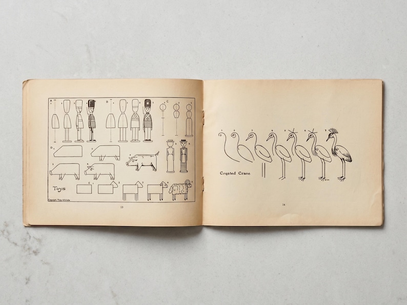 May include: An open vintage book with illustrations of toys and a crested crane. The left page shows step-by-step drawings of toy soldiers, pigs, sheep, and other figures. The right page features a series of drawings of a crested crane.