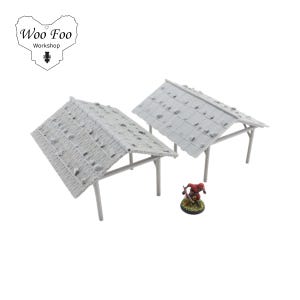 K&ouml;nnte beinhalten: Zwei Miniaturstrukturen in Grau mit Strohd&auml;chern und St&uuml;tzbeinen sowie eine kleine Figur einer Person in roter Kleidung. Die Strukturen sind f&uuml;r Tabletop-Spiele konzipiert. Das Logo "Woo Foo Workshop" befindet sich in der oberen linken Ecke.