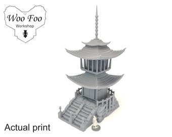 May include: A grey 3D printed model of a two-storey pagoda with a pointed roof and a small figure standing in front. The pagoda has a wooden door and windows, and the roof is decorated with intricate details. The model is printed in a light grey colour and is set against a white background.