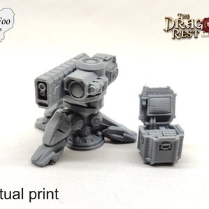 Può includere: Un modello di torretta d'arma futuristica stampato in 3D con una scatola di munizioni. La torretta è grigia e presenta un design dettagliato. La scatola è anch'essa grigia e ha un coperchio incernierato.