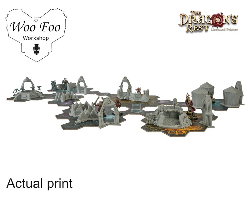 May include: A tabletop gaming terrain set featuring various gray structures, including arches, towers, and rocky formations, arranged on hexagonal tiles. The set includes miniature figures. The text "Woo Foo Workshop" and "The Dragon's Rest" are visible.