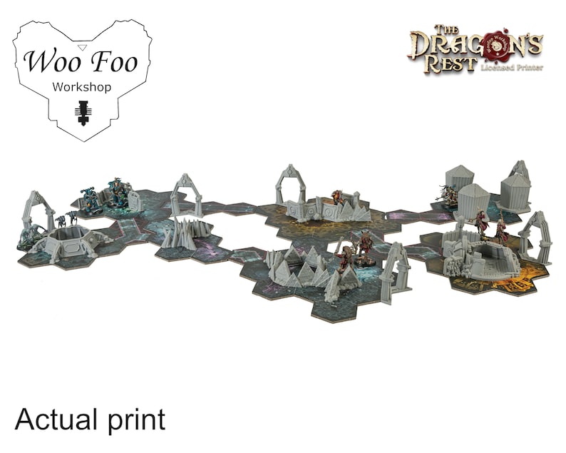May include: A tabletop gaming terrain set featuring hexagonal tiles and miniature figures. The set includes gray archways, structures, and figures on a dark, textured surface. The text "Woo Foo Workshop" and "The Dragon's Rest" are visible.