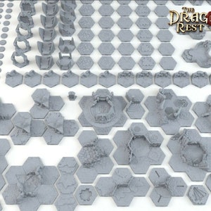 May include: A set of 3D printed dungeon tiles for tabletop role-playing games. The tiles are gray and feature various ruined structures and details. The set includes a variety of shapes and sizes, including squares, hexagons, and circles. The tiles are designed to be used with The Dragon's Rest Licensed Printer.