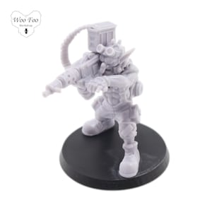 Puede incluir: Una figura en miniatura de plástico gris de una criatura parecida a un goblin que sostiene un arma futurista. La figura está de pie sobre una base circular negra.