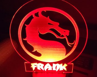 Könnte beinhalten: Ein rotes und gelbes Nachtlicht mit einem Drachenlogo und dem Namen "FRANK" auf dem Sockel.