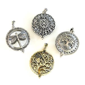 May include: Four silver and gold-toned pendants with detailed designs. One shows a dragonfly, another a circular pattern, a third a tree of life, and the last an owl in a tree. Each pendant has a loop for a chain, suitable for necklaces.