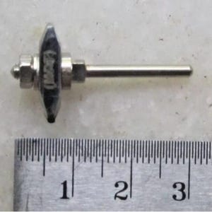 Peut inclure: Un outil en métal avec une tête pointue gris foncé et une tige argentée qui s'en écarte. La tête porte l'inscription "Macher". L'outil mesure environ 7,6 cm de long.