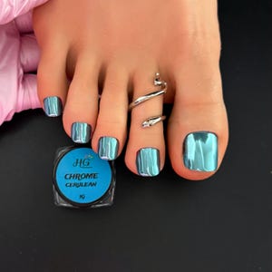May include: A close-up of a foot with teal chrome nail polish and a silver snake toe ring. A small container of "Chrome Cerulean" nail powder is visible. The nails have a shiny, metallic finish.