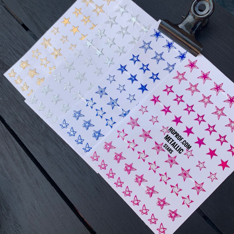 May include: Four sheets of metallic star stickers. The stickers are in gold, silver, blue, and pink. The sheets are labeled "HGPROF.COM METALLIC STARS".