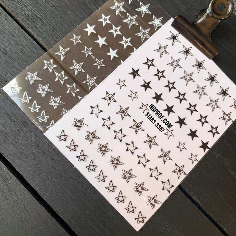 May include: Two sheets of nail art stickers with different star designs. One sheet has white stars on a clear background. The other sheet has black stars and geometric star designs on a white background. The text on the sheet reads "HGPROF.COM STARS-3357".
