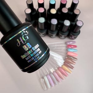 May include: A black bottle of HG BB Builder Base self-levelling nail polish, 15ml. The image also shows a variety of nail polish colours on clear swatch sticks and several other bottles of nail polish in the background.