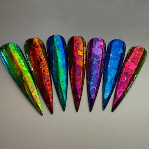May include: Seven iridescent nail foils in various colors, including green, blue, red, and purple. The foils have a holographic finish and are designed for nail art.