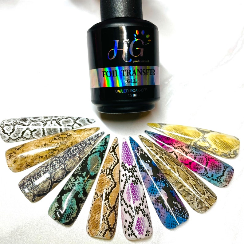 Op de afbeelding: Een fles HG Professional Foil Transfer Gel, een heldere gel met een zwarte dop, en 12 nagelkunstontwerpen met een slangenhuidpatroon in verschillende kleuren. De fles is gelabeld met "HG Professional Foil Transfer Gel" en "UV/LED Soak Off 15 ml".