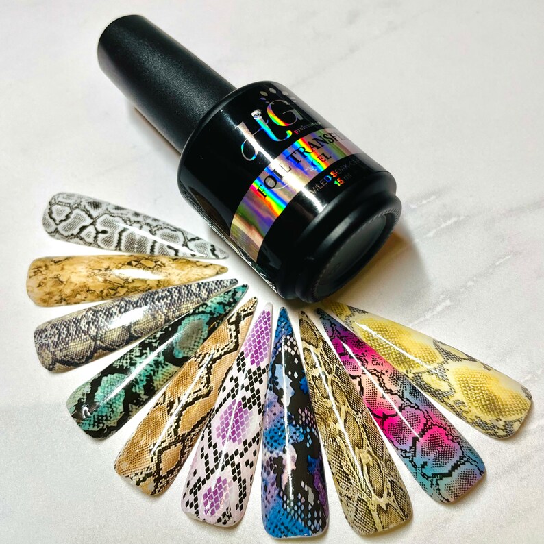 Op de afbeelding: Een flesje met heldere nagellak met een zwarte dop en een holografisch etiket met de tekst "Foil Transfer Gel". De fles is omringd door 12 nageltips met verschillende slangenhuidpatronen in verschillende kleuren, waaronder zwart, wit, bruin, paars, blauw en groen.