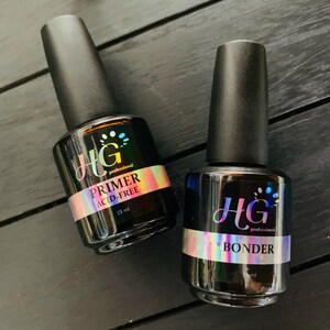 Puede incluir: Dos botellas de 15 ml de productos para el cuidado de las uñas. La botella de la izquierda está etiquetada como "HG professional PRIMER ACID-FREE". La botella de la derecha está etiquetada como "HG professional BONDER".