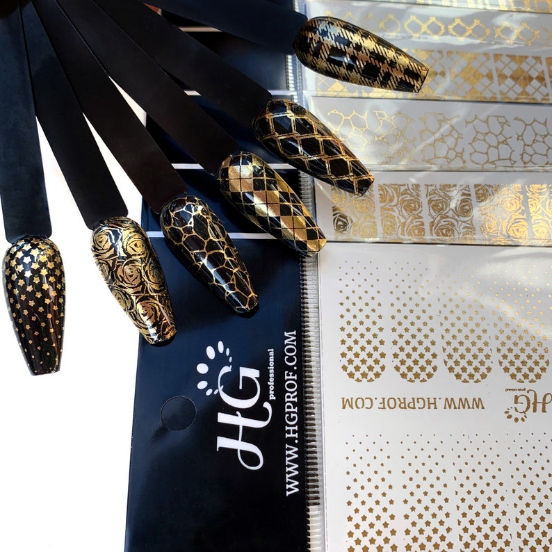 Puede incluir: Un conjunto de pegatinas doradas para el arte de u&ntilde;as con varios dise&ntilde;os, incluyendo estrellas, patrones geom&eacute;tricos y motivos florales. Las pegatinas se muestran sobre un fondo negro con el nombre de la marca "HG" y la direcci&oacute;n del sitio web "www.hgprof.com".