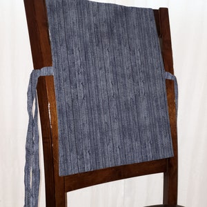 May include: A dark wood chair with a blue and white striped fabric chair back cushion. The cushion has ties to attach it to the chair.