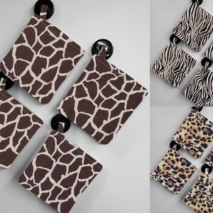May include: Four brown and white patterned fabric pouches with black button closures. The pouches have a giraffe print.