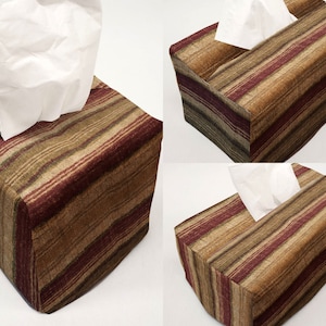 May include: A brown and burgundy striped tissue box cover. The cover has a slot for tissues to be pulled out.