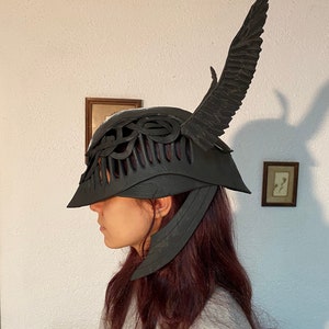 May include: A black helmet with a wing design on the side. The helmet has a detailed, intricate design and appears to be made of a hard material.
