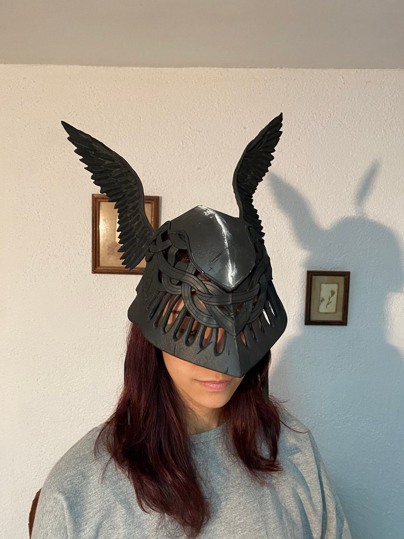 May include: A black, 3D printed helmet with intricate details and wings. The helmet is made of a lightweight material and has a unique design.