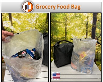 May include: A clear, lightweight grocery food bag made in the USA. The bag is filled with various food items and is shown next to a black, waterproof bag.