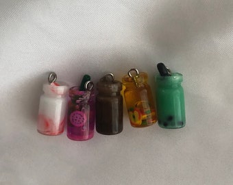 May include: Six miniature glass jars with different colored liquids and decorative elements inside. The jars are on a white background and have silver tops.