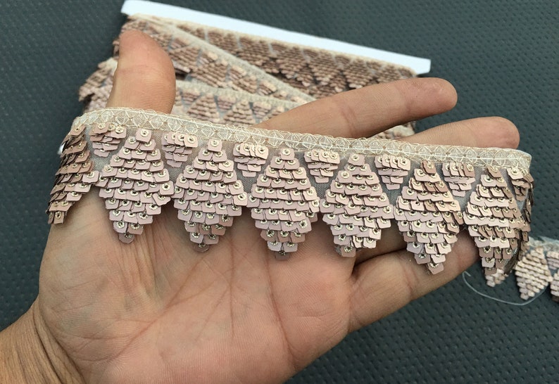 Puede incluir: Primer plano de un ribete de lentejuelas rosa con borde festoneado. El ribete est&aacute; hecho de peque&ntilde;as lentejuelas iridiscentes cosidas sobre una tela de malla transparente.