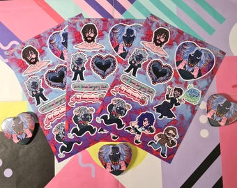 May include: Sheets of stickers and heart-shaped buttons featuring cartoon characters with dark hair and a black and white creature. The stickers have a purple and red marbled background. Text includes "And Demon Loves to All".