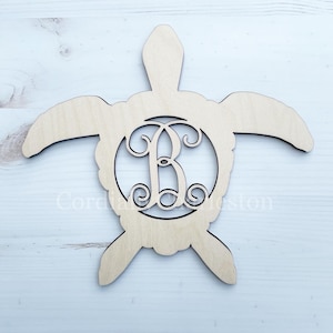 May include: A wooden turtle-shaped monogram with the letter "B" in a decorative font. The turtle is light brown and has a circular cutout in the center with the letter. The design is suitable for home decor.