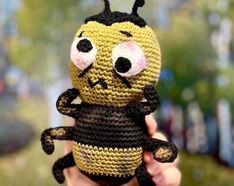 May include: A crocheted bee toy with black and yellow stripes, large eyes, and a worried expression.