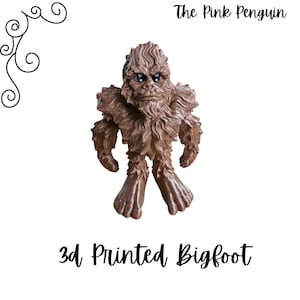 May include: A 3D printed brown Bigfoot figurine. The figurine is standing with its arms at its sides and has a furry texture. The figurine is about 4 inches tall.