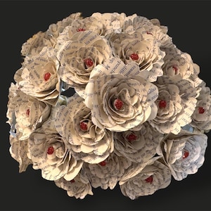 May include: A bouquet of paper flowers made from book pages. The flowers are white with red centers. The bouquet is arranged in a circular shape.