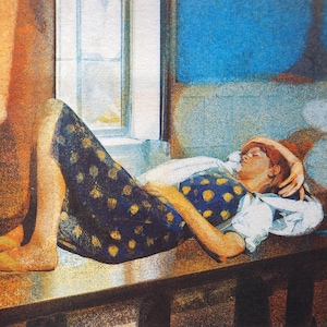 May include: A woman in a blue and yellow polka dot dress lies on a wooden table with her head resting on her arm. The woman has red hair and is wearing a white shirt. The table is in a room with a window and a blue wall.