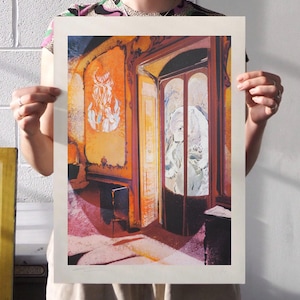 Könnte beinhalten: Ein gerahmter Druck einer Innenszene in warmen Orange- und Rosatönen. Das Kunstwerk zeigt einen Raum mit einer Tür und einer durch das Glas sichtbaren Figur. Der Druck hat einen weißen Rand und wird vor einer weißen Wand gehalten.